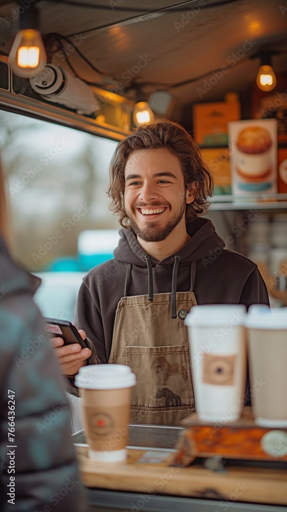 Coffee truck barista with a cheerful smile accepting a contactless payment from a customer Coffee truck barista with a cheerful smile accepting a contactless payment from a customer
