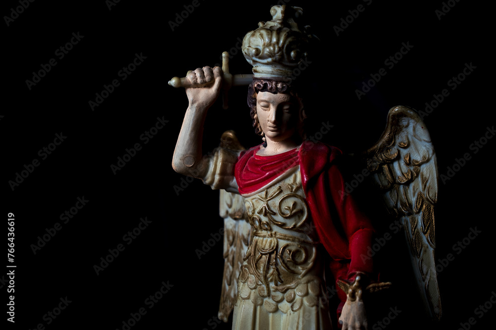 Saint Michael Archangel statue fighting the devil with sword in black background Saint Michael Archangel statue fighting the devil with sword in black background