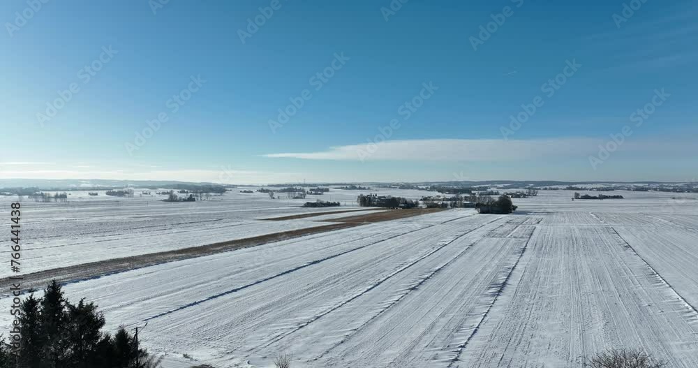 Krajobraz wiejski zimą z lotu ptaka, pola oraz niebieskie niebo w zimie pola pokryte śniegiem oraz cały krajobraz w białym kolorze Krajobraz wiejski zimą z lotu ptaka, pola oraz niebieskie niebo w zimie pola pokryte śniegiem oraz cały krajobraz w białym kolorze
