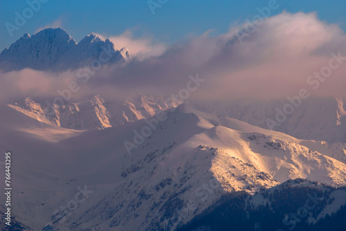 Mountains Landscape in winter. Tatra National Park- view from Czarna Gora. Mountain peaks illuminated by the rays of the setting sun shining through the clouds. Spisz. Malopolskie. Poland.