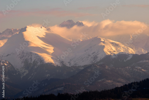 Mountains Landscape in winter. Tatra National Park- view from Czarna Gora. Mountain peaks illuminated by the rays of the setting sun shining through the clouds. Spisz. Malopolskie. Poland.