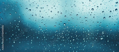 Rain droplets are seen on a window glass  with a clear blue sky in the background creating a serene and calm atmosphere