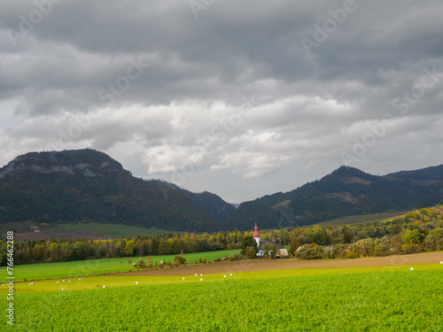 Landscape with dramatic sky. View of the Hoczańskie Mountains. In the foreground, a farmland and Church of Sv. Ladislav in Liptowskie Matiaszowce. Zilina Region. Liptowskie Matiaszowce. Slovakia. photo