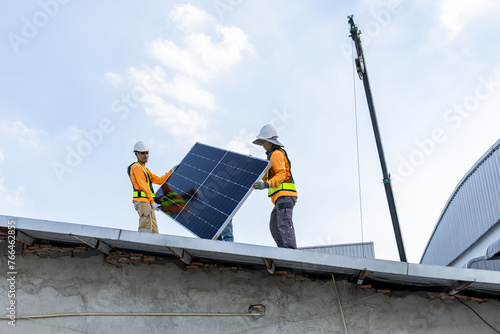 Technicians Install photovoltaic solar modules on roof of factory. Engineers install or fix solar cells in roof of factory. Technician worker on solar panels. Solar technician working on factory roof