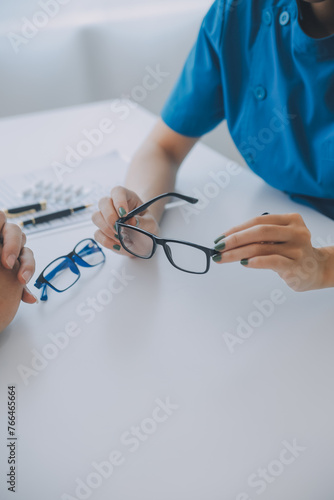 Close-up of Asian female doctor talking with elderly patient showing eyeball model and explaining eye disease in hospital