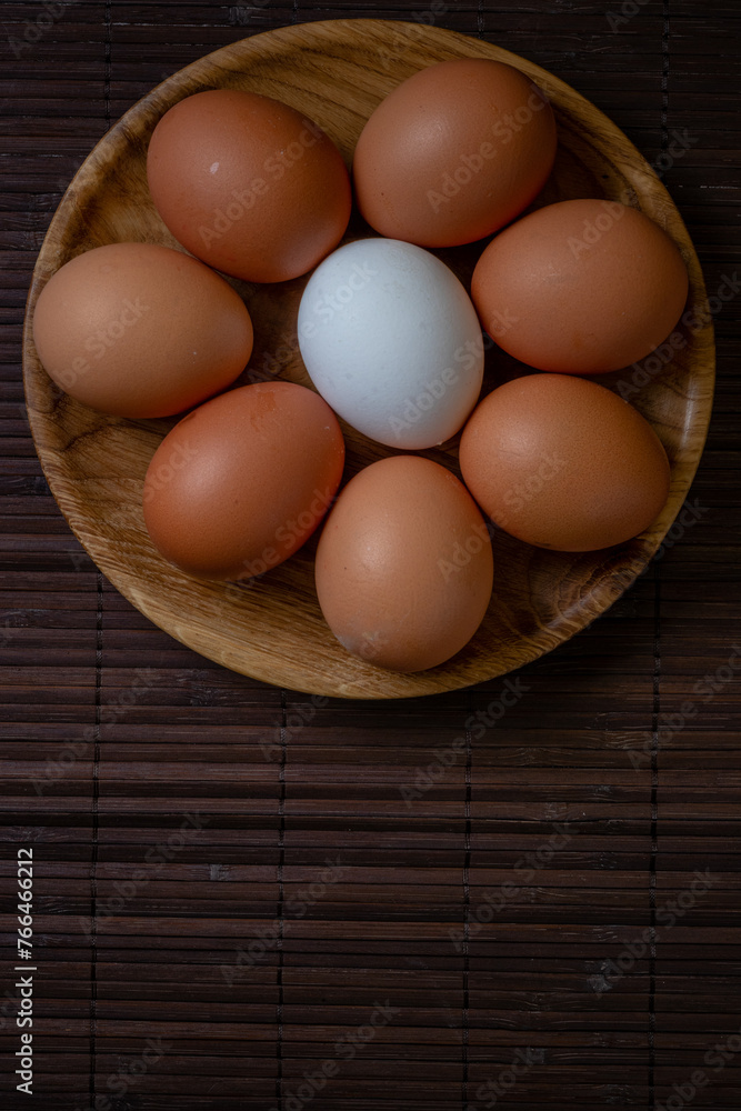 Fresh chicken eggs in wooden plate on the table, selective focus Fresh chicken eggs in wooden plate on the table, selective focus