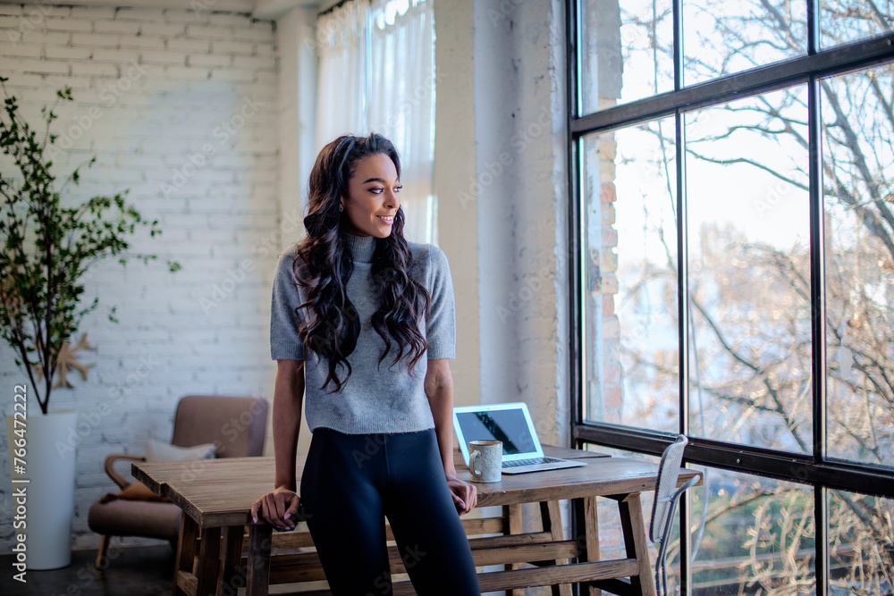 Portrait of an afro-american woman wearing casual clothes and standing at the window