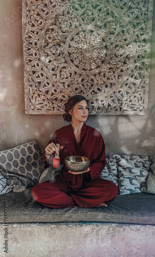 a beautiful woman yogi moves a stick along a singing Indian bowl