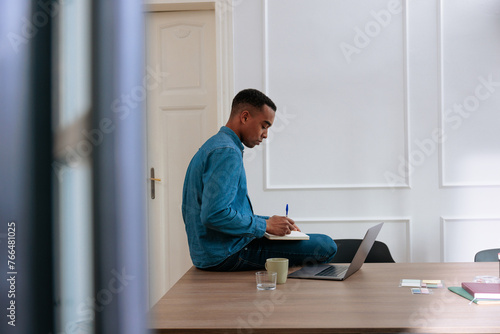 Male office worker sitting on the table writing notes