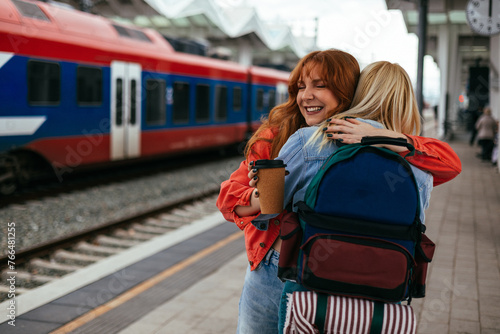 Friends hugging with train behind them at the station