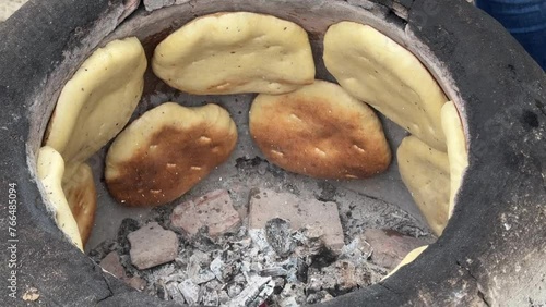 Woman Baking Traditional Tunisian Bread (Tabouna) in a Terracota Oven (Tabouna) photo