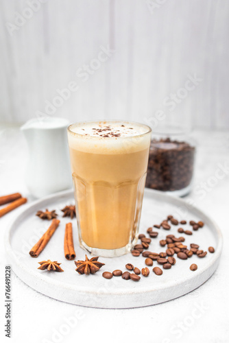 Coffee latte in glass with cinnamon, spices and roasted coffee beans. Creamy coffee with milk. Coffee drink recipe. 