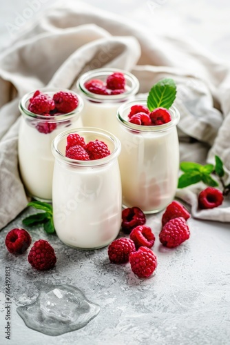 Three glasses of yogurt with fresh raspberries on a wooden table, suitable for food and beverage concepts