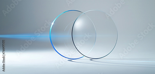 An optically clear, thin fu ll glass circle, seen from a side angle with a rotated perspective. a blue line of light shines through the circle and stands against a pristine white background