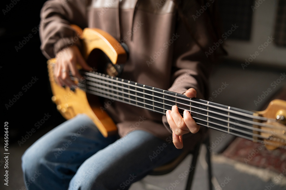 Fototapeta premium Close-Up View of a Musician Playing a Bass Guitar During an Indoor Session