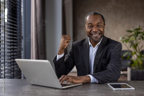 Portrait of mature experienced man businessman winner, senior african american boss joyful looking at camera, holding hands up in triumph gesture, celebrating successful achievement results.