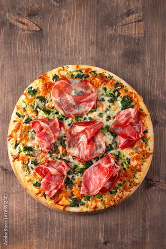 Pizza with prosciutto, ham, arugula, tomatoes, pesto, cheese and parmesan. Italian cuisine. 