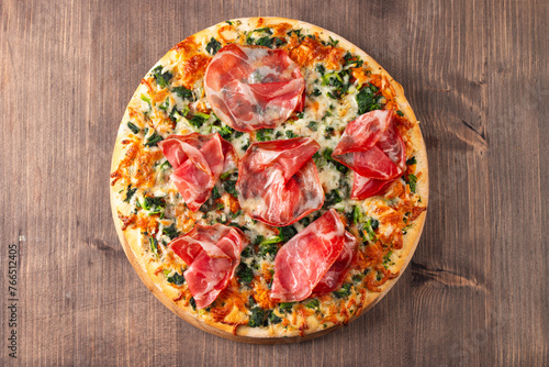 Pizza with prosciutto, ham, arugula, tomatoes, pesto, cheese and parmesan. Italian cuisine. 