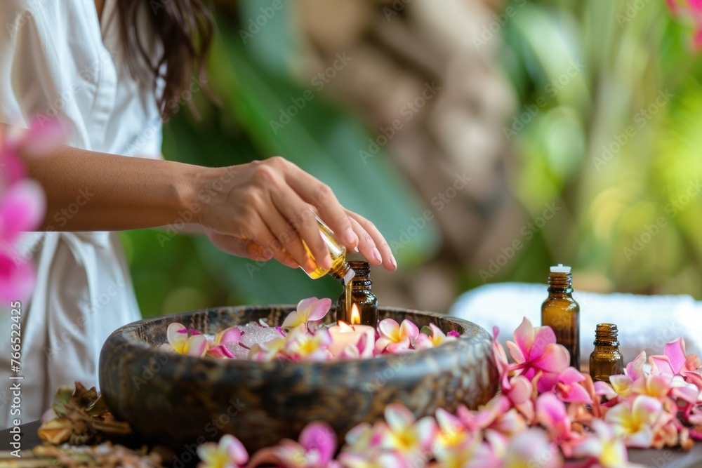 Spa therapist pouring essential oil into ceramic bowl with floating flowers for rejuvenating massage therapy session at luxury spa. - obrazy, fototapety, plakaty 