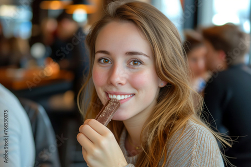 Young beautiful woman eating chocolate bar in a cafe. Close up portrait