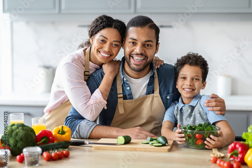 Family portrait of black parents cooking with their son