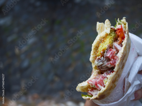 Authentic street food: falafel sandwich with pita bread, hummus, tomatoes, and lettuce