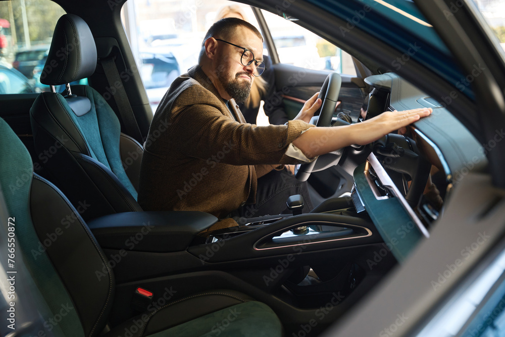 Guy stroking the dashboard of a new car