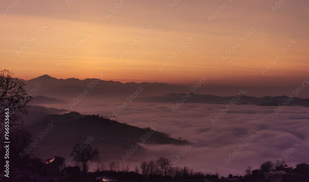 Fototapeta premium Un mare di nuvole bianche e di nebbia riempie le valli sotto le montagne al tramonto 