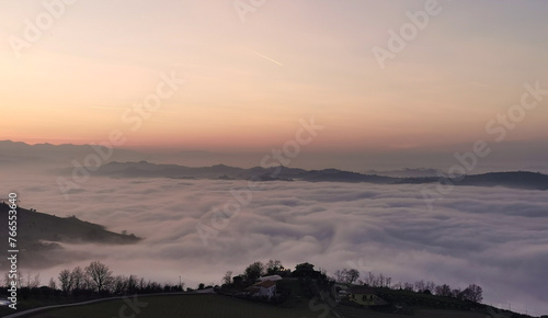 Un mare di nuvole bianche  e di nebbia riempie le valli sotto le montagneal tramonto  photo