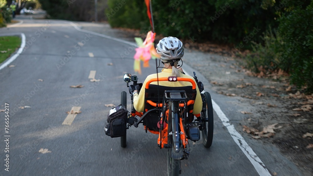 Closeup rear view of elderly senior woman riding a recumbent electric bike on a bike path in Southern California. Filmed in.