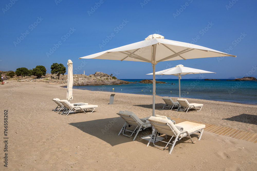Sunbeds with umbrella on sandy beach of Agios Stefanos. The Greek island of Kos Sunbeds with umbrella on sandy beach of Agios Stefanos. The Greek island of Kos
