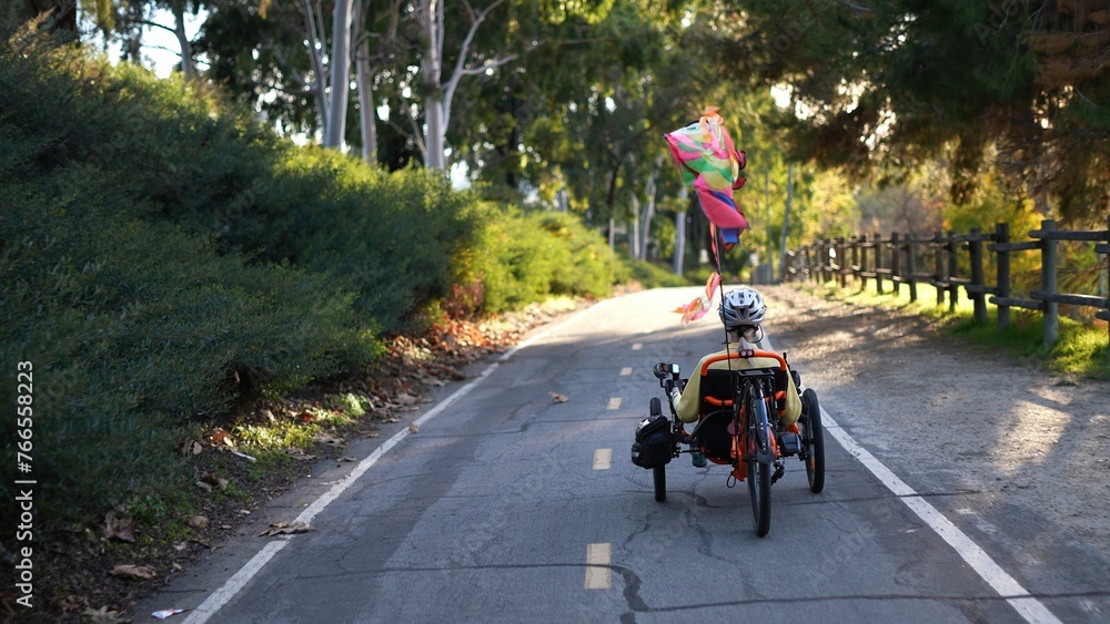 Naklejka premium Rear view of mature woman riding a recumbent electric bike on a bike path in Southern California. Filmed in.