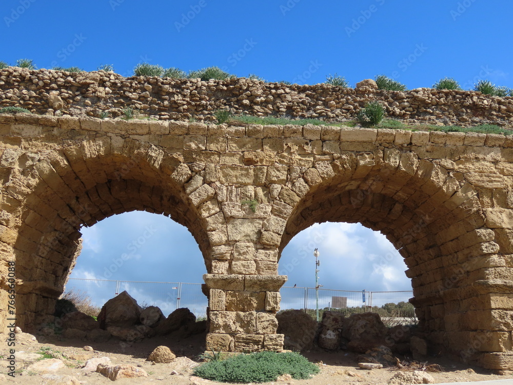 Ancient Roman aqueduct in Caesarea against the blue sky. Traveling around Israel.