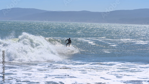 Surfer on a wave from sand Beach of Pelline during summer (Maule region, Chile)