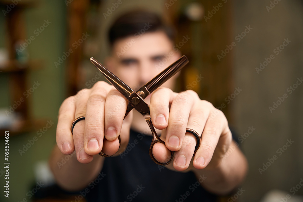 Blurred barber showing scissors in barbershop