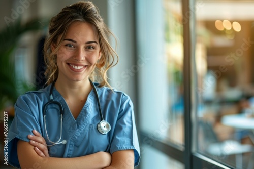 A woman in a blue scrubs is smiling and posing for a picture