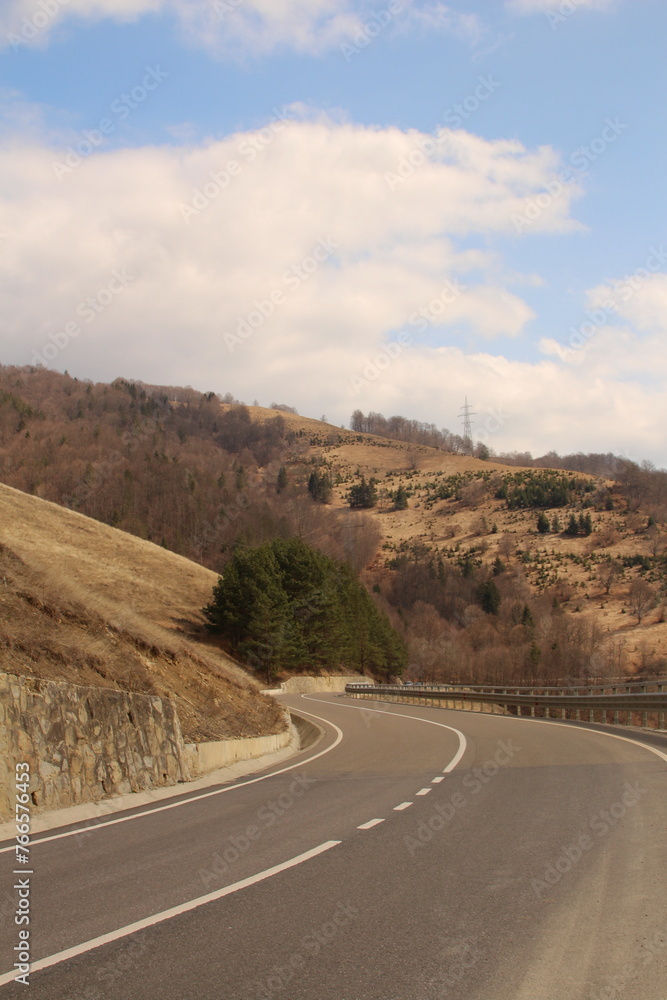 A road with hills and trees on either side of it A road with hills and trees on either side of it