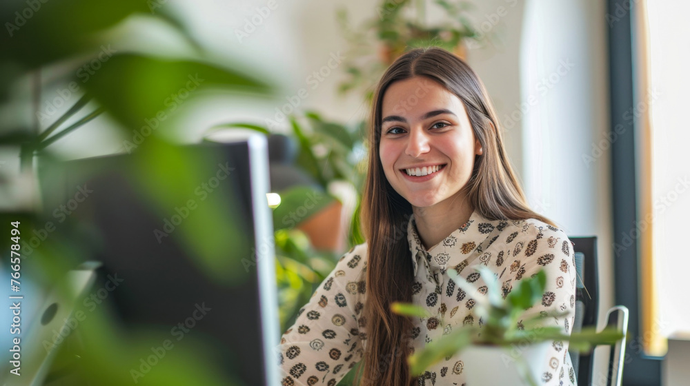 Smiling young woman working on computer in a green office environment Smiling young woman working on computer in a green office environment