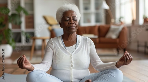 Senior woman practicing yoga with a focused expression in a tranquil home environment.