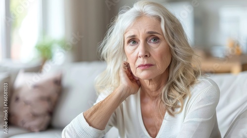 Concerned senior woman with white hair and blue eyes at home.