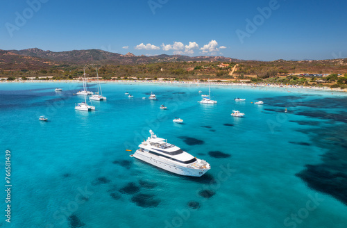 Aerial view of luxury yachts on blue sea and sandy beach © ali
