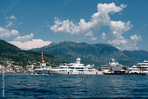 Luxurious white superyachts stand at Porto marina with mountains in the background
