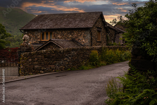 Beautiful warm sunset bathes a traditional stone cottage in the Lake District