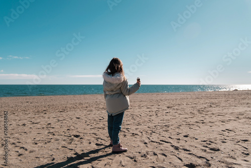 Playa Andalucía, niña con chaquetón en la arena tomando un helado