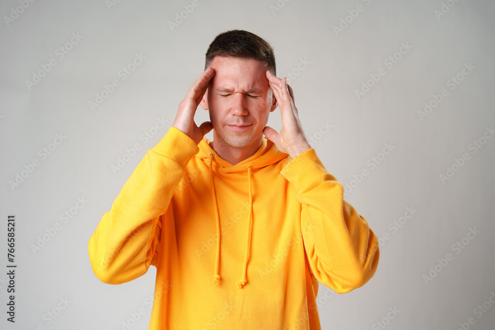 Young handsome man standing over gray background suffering from headache Young handsome man standing over gray background suffering from headache