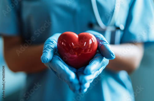 Doctor in blue scrabs holding a red heart in gloved hands. Cardiology care and health awareness concept. Design for medical brochure, heart health campaign, or hospital service poster. photo