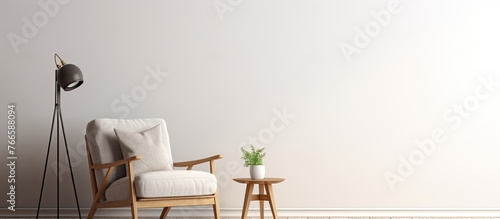 In a room  there is a white chair placed beside a table that has a lamp on top of it