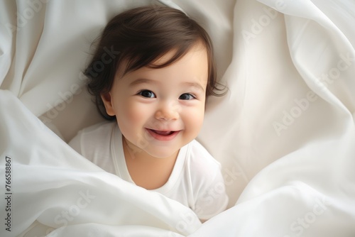 Cute baby lies in a white bed. Bright nursery for small children. Smiling child