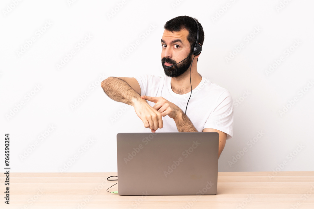 Telemarketer caucasian man working with a headset and with laptop making the gesture of being late. Telemarketer caucasian man working with a headset and with laptop making the gesture of being late.