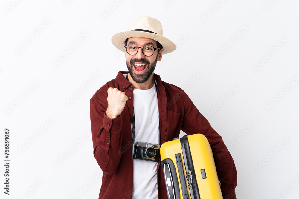 Traveler man man with beard holding a suitcase over isolated white background celebrating a victory in winner position Traveler man man with beard holding a suitcase over isolated white background celebrating a victory in winner position